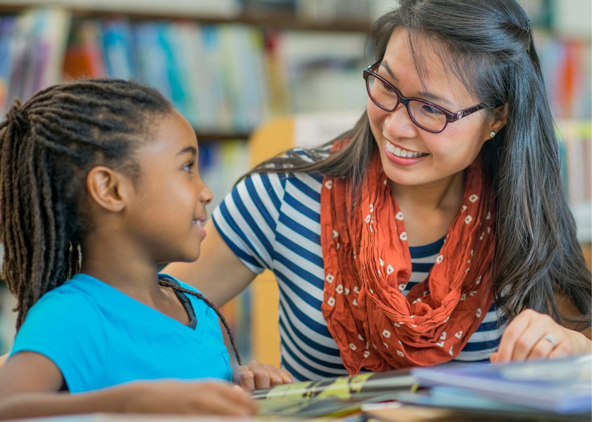 A tutor working one to one with a young student in a library